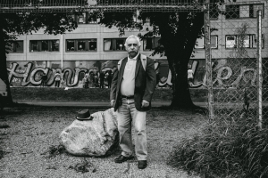 Photo of poet José H Romero in front of a graffiti of the word "Hammarkullen" futuro berg