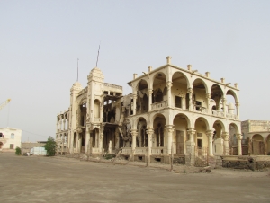 Ruin of the Bank of Italy building, Massawa, completed in the 1920s and heavily damaged during the war between Ethiopia and Eritrea. The cranes show that the harbour is in use despite all ruined buildings around. Photo: Soroor Notash. February 2019